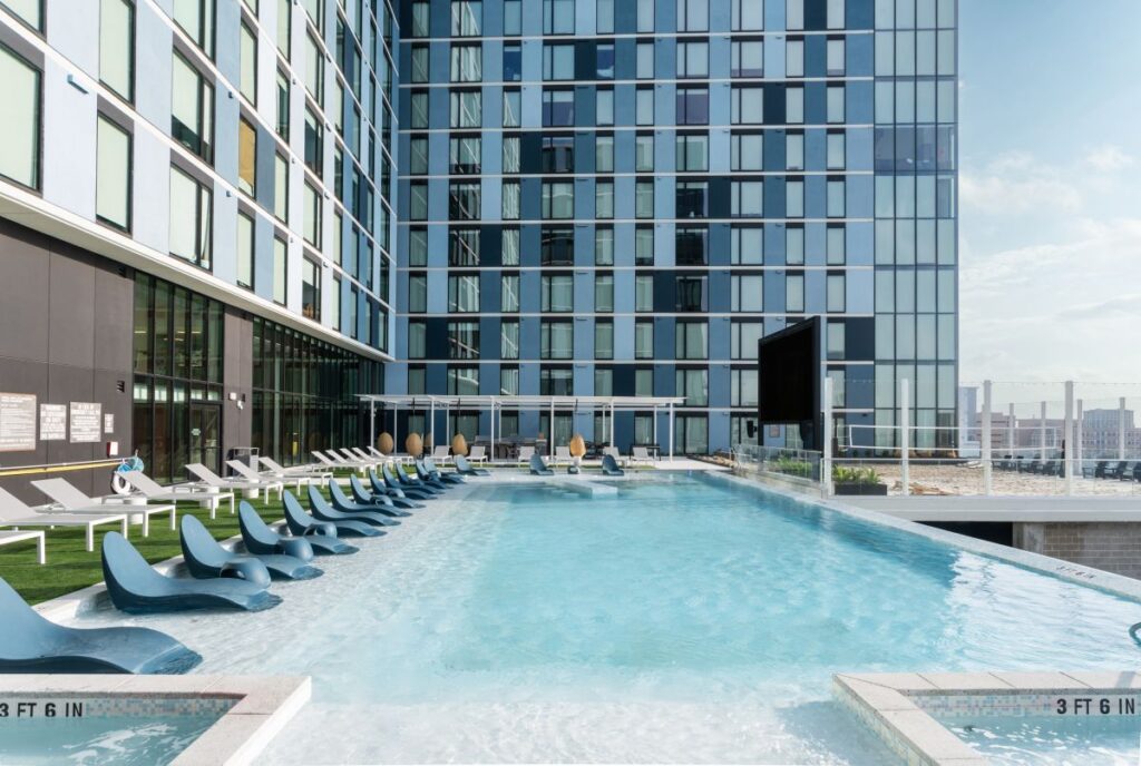 Rev Student Living near TAMU: Outdoor view of Resort-style Pool Courtyard with Semi-submerged Daybeds- Now Leasing Studio and 1 Bedrooms for Students and Grad Students